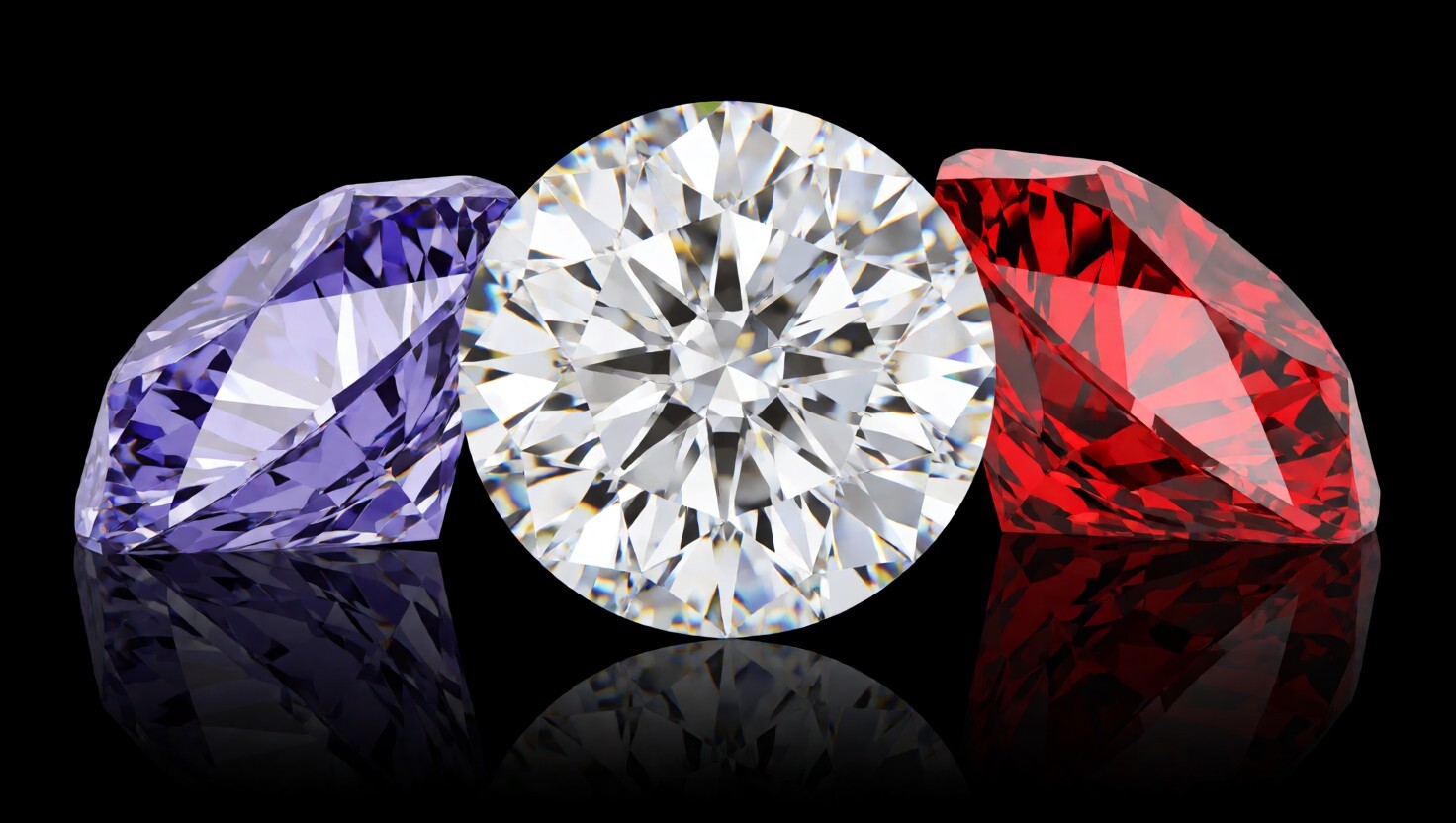 Purple, clear, and red faceted diamonds reflected on a black surface